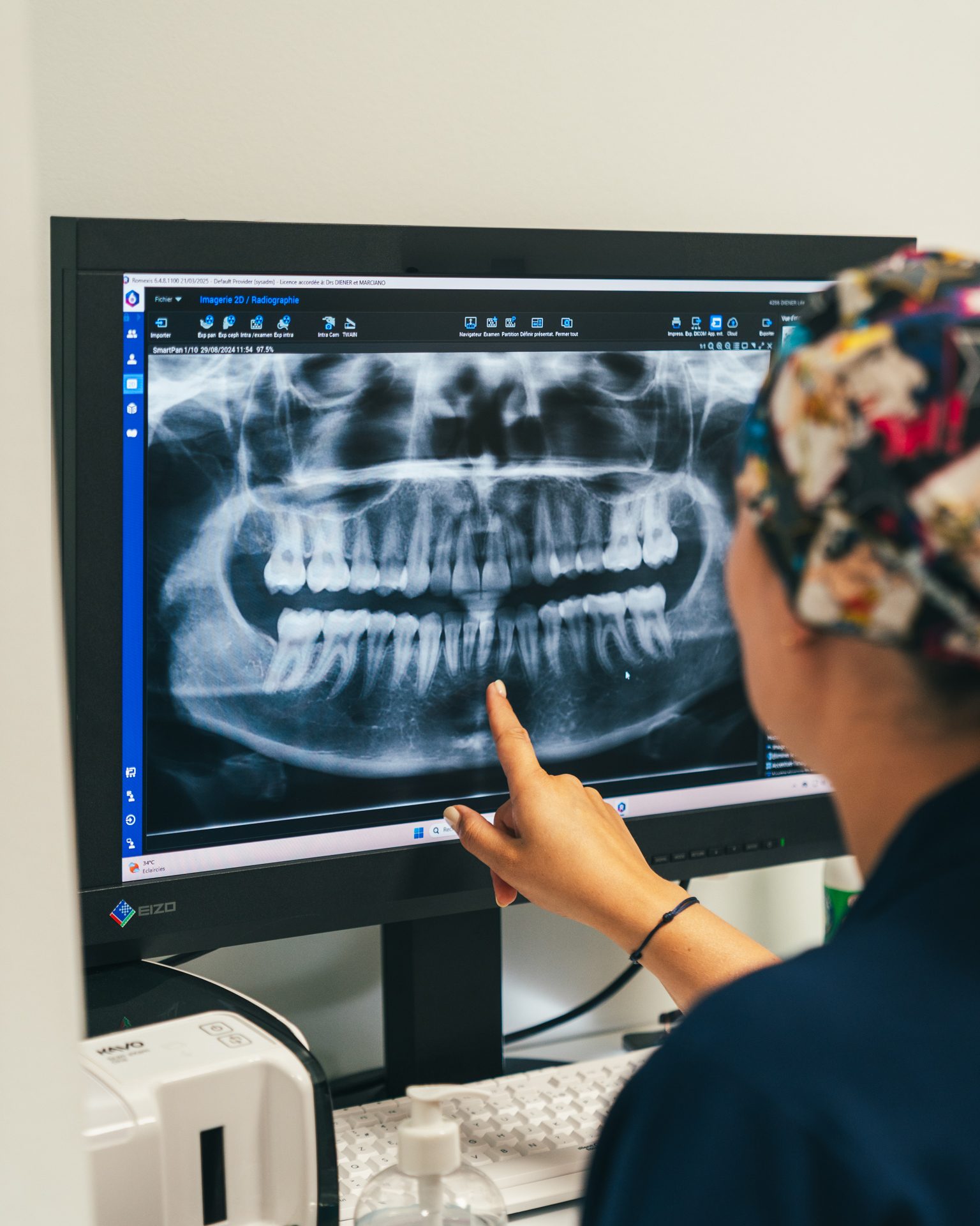 Praticienne expliquant une radiographie panoramique affichée sur un écran